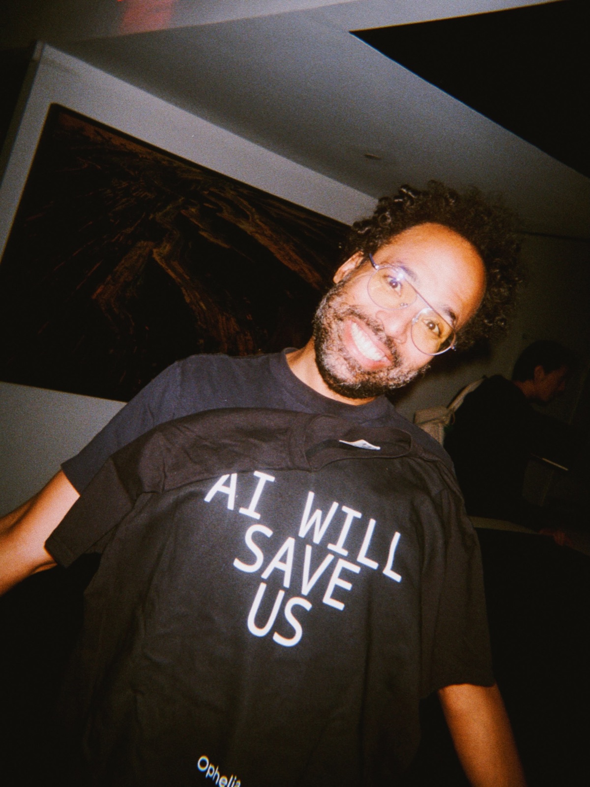 A guest holds up a black t-shirt that reads AI will save us