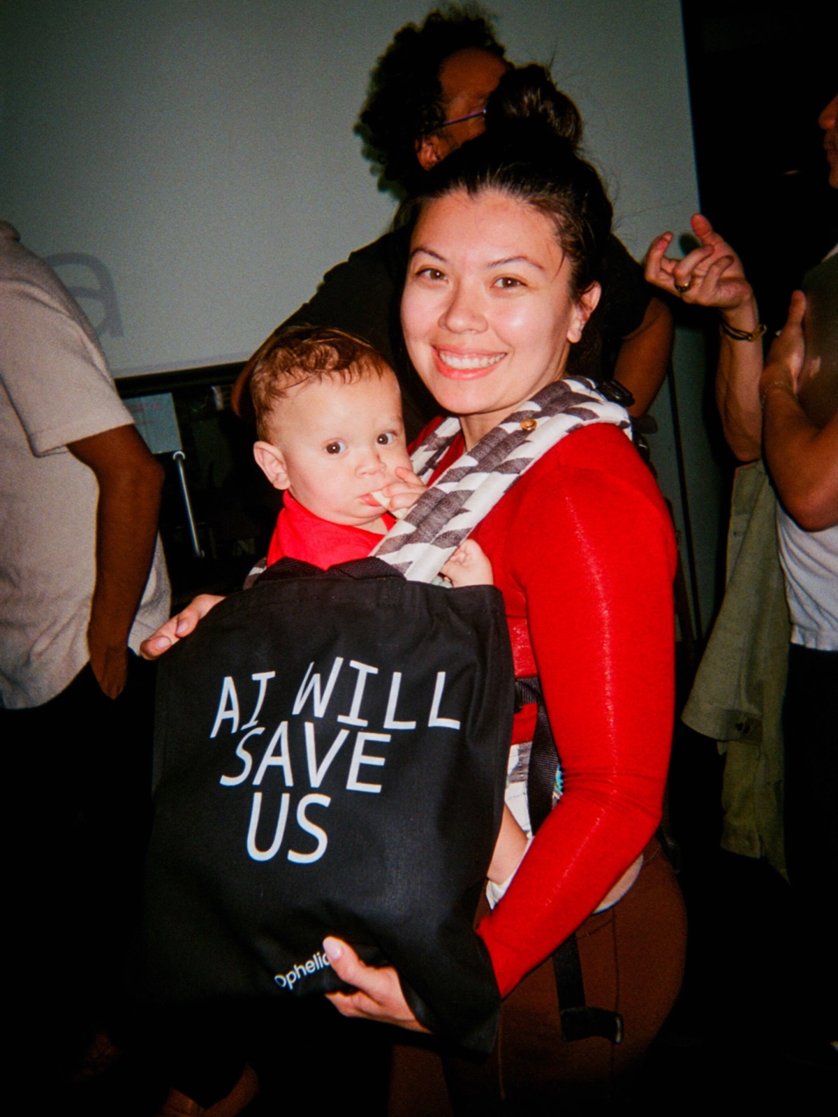 A guest holding a toddler carries an AI will save us tote bag