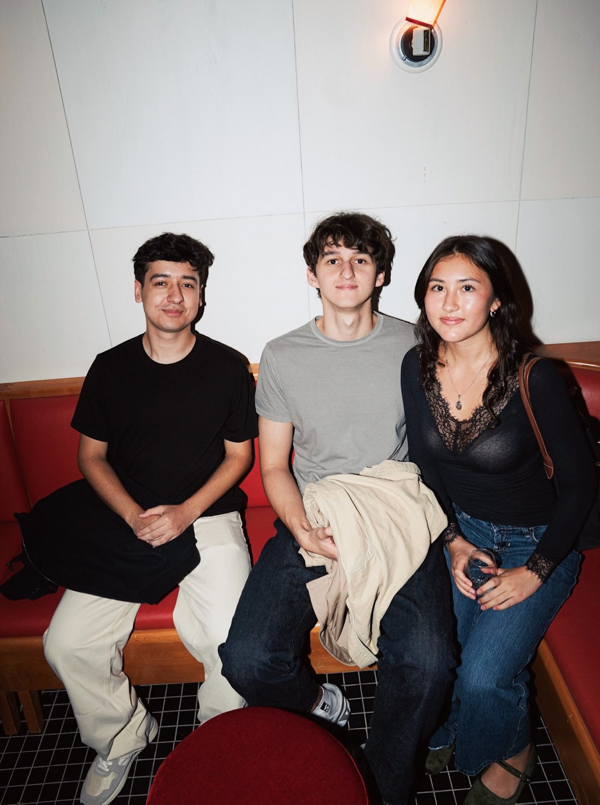 Three guests sit together on a red banquette