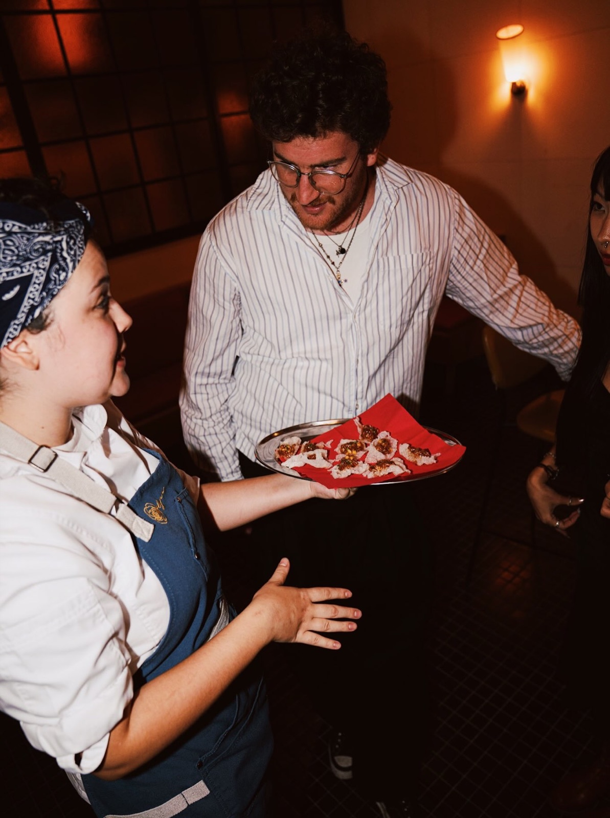 A host offers a tray of food to a guest