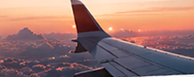 Airplane wing above clouds at sunset